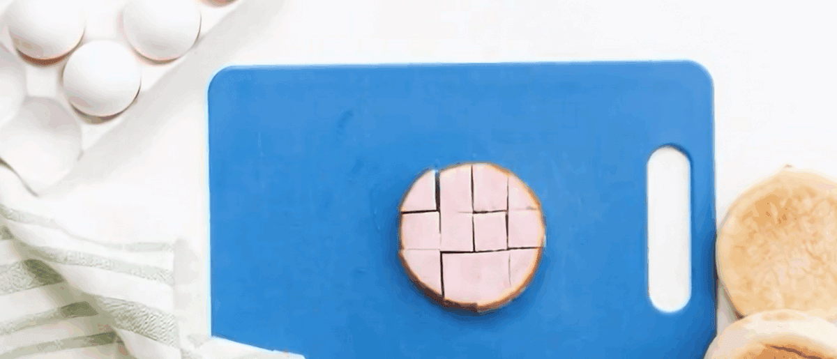 Chopping Canadian bacon on a blue cutting board.