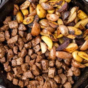 Overhead view of steak bites and potatoes in a skillet