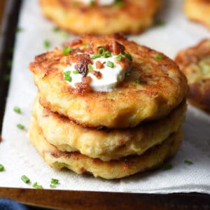 stacked of 3 mashed potato cakes topped with sour cream and bacon