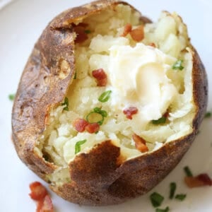 baked potato split open with butter, bacon, and scallions