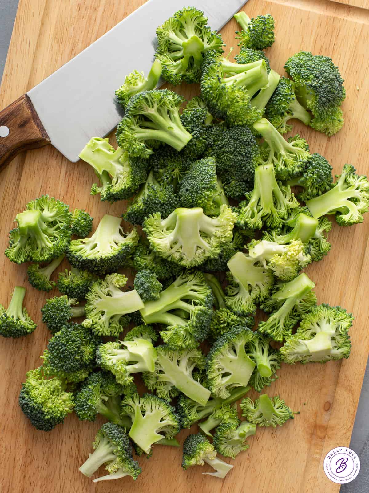 pile of raw broccoli florets on cutting board