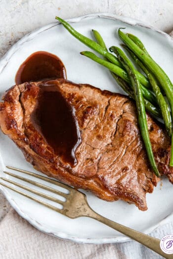 pan seared steak on plate with sauce and green beans