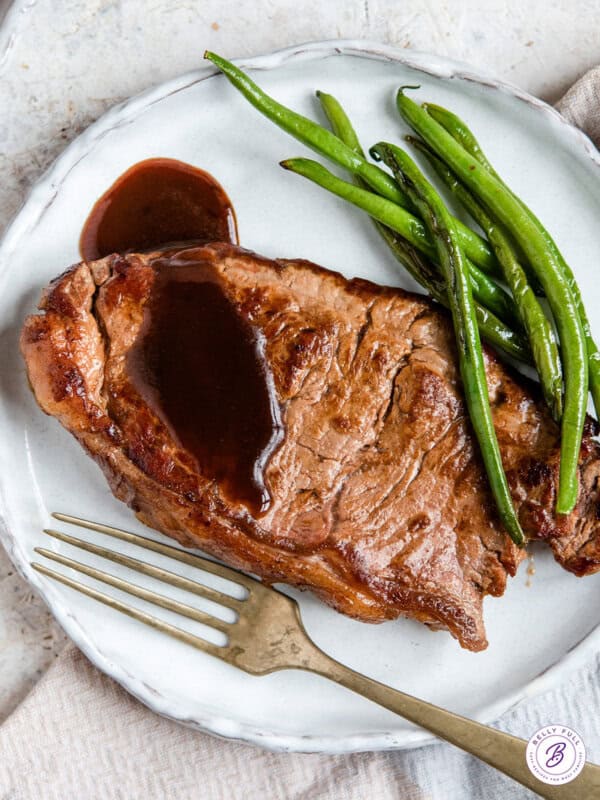 pan seared steak on plate with sauce and green beans