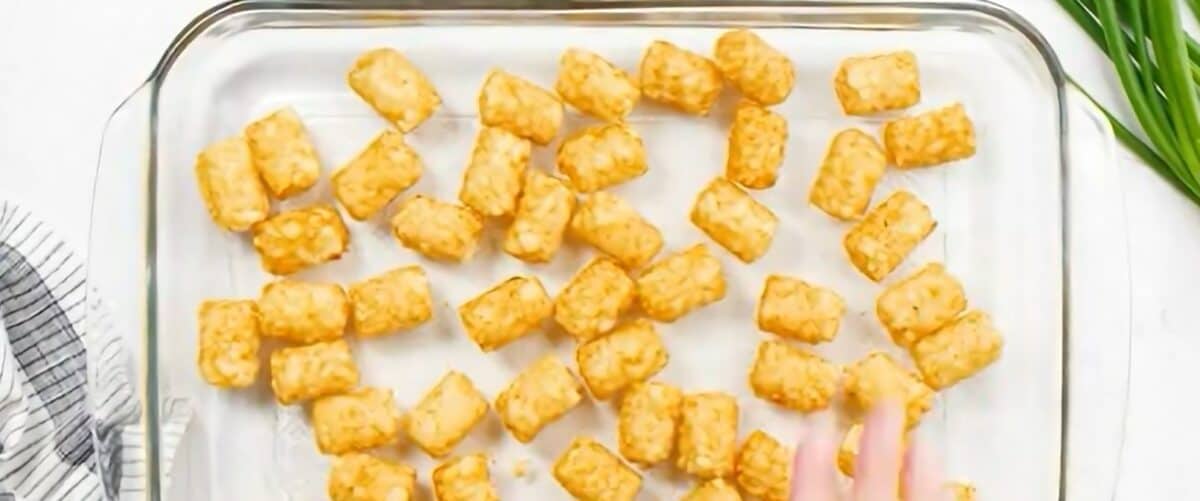 Spreading tater tots in a baking dish.