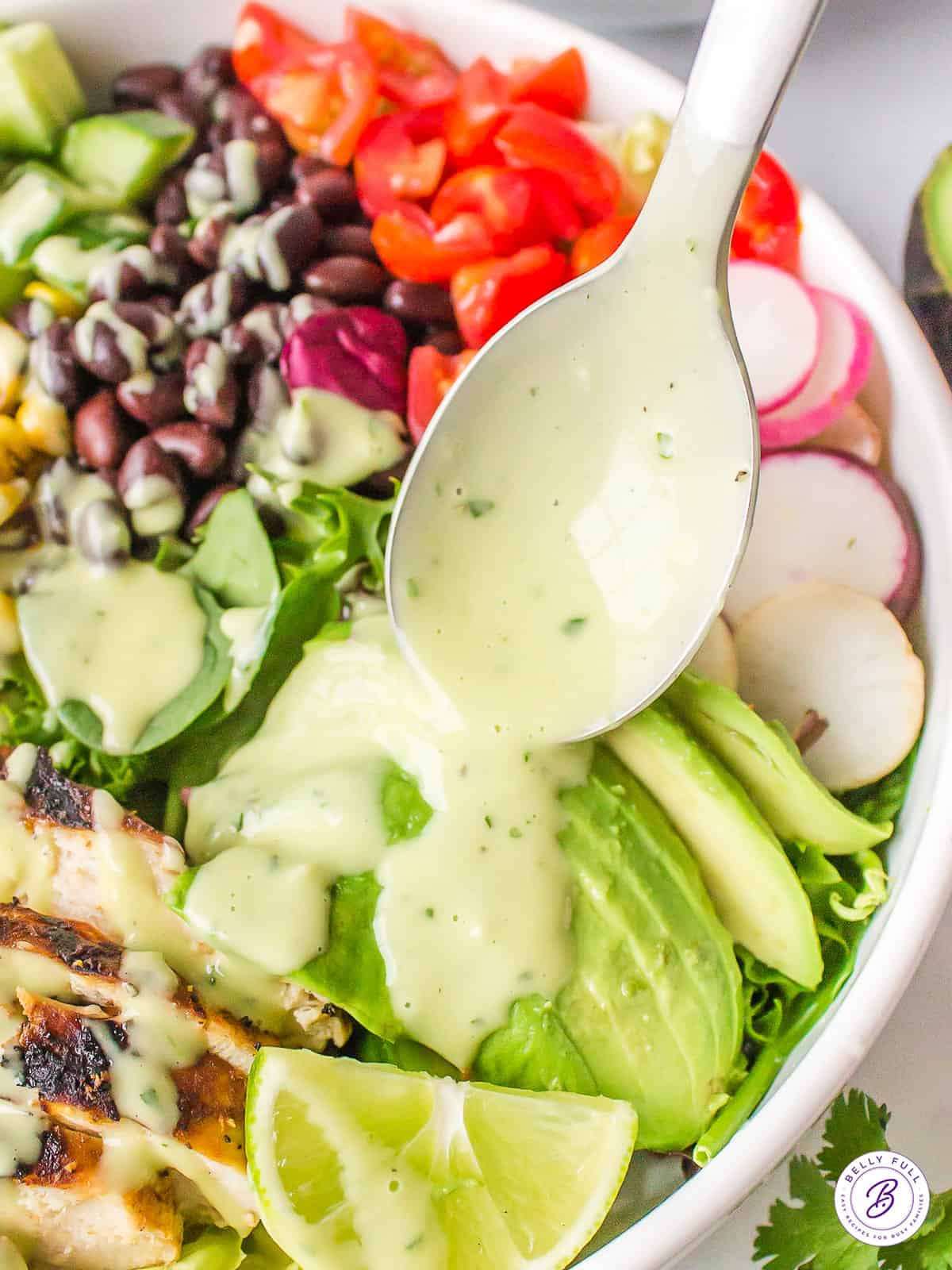 creamy cilantro-lime dressing being spooned over salad