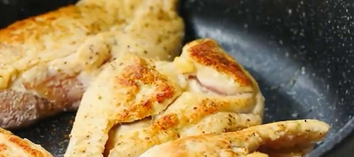 Pan frying the coated chicken breasts.