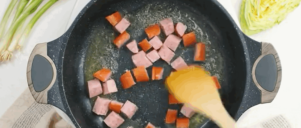 Cooking the sausage in a black skillet.