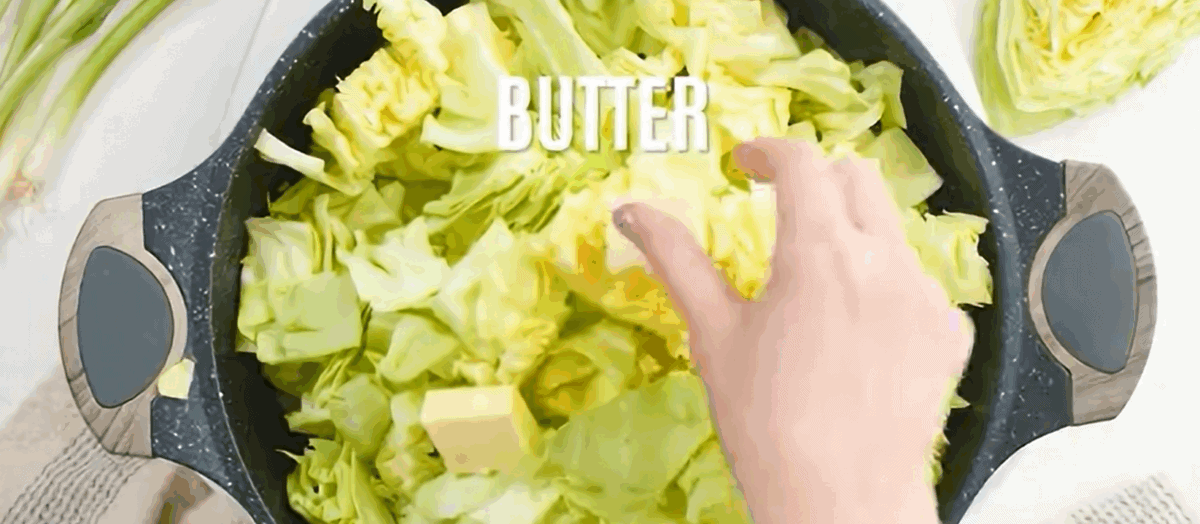 Sauteeing cabbage in butter in a black skillet.