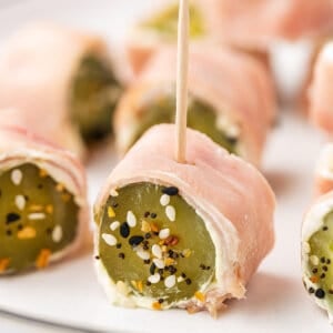 A dill pickle roll up with a toothpick on a plate