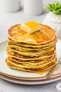 Tall stack of zucchini ricotta pancakes with slab of butter