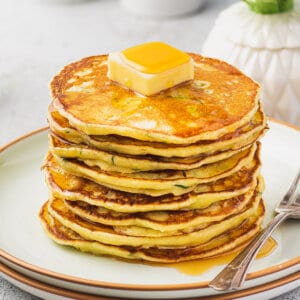 Tall stack of zucchini ricotta pancakes with slab of butter