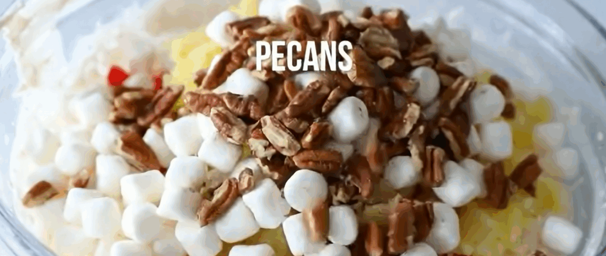 Adding cherries, pineapple, marshmallows, and pecans to the cream cheese mixture.