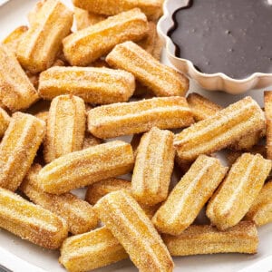 Overhead view of a plate of churro bites with a dish of chocolate sauce