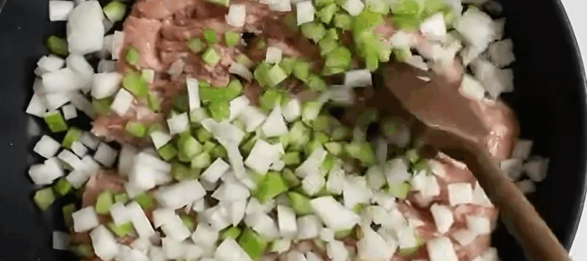 Cooking ground chicken, onions, and celery in a black skillet.