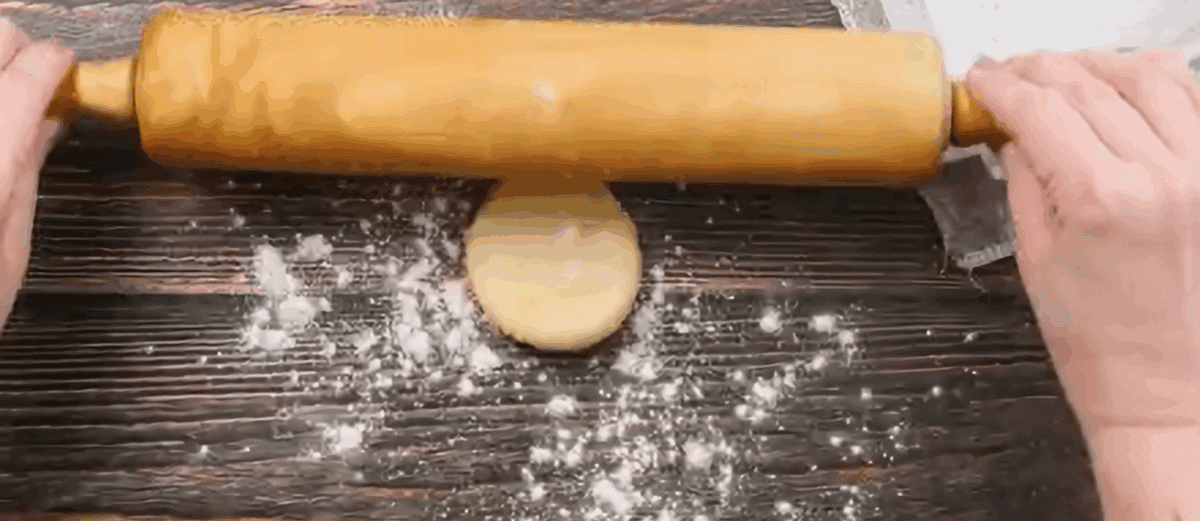 A rolling pin rolling out the dough ball.