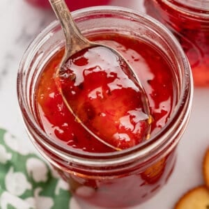 A spoon in a jar of red pepper jelly