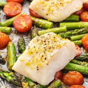 baked cod over roasted tomatoes and asparagus on sheet pan