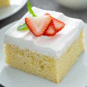 piece of tres leches cake garnished with sliced strawberries