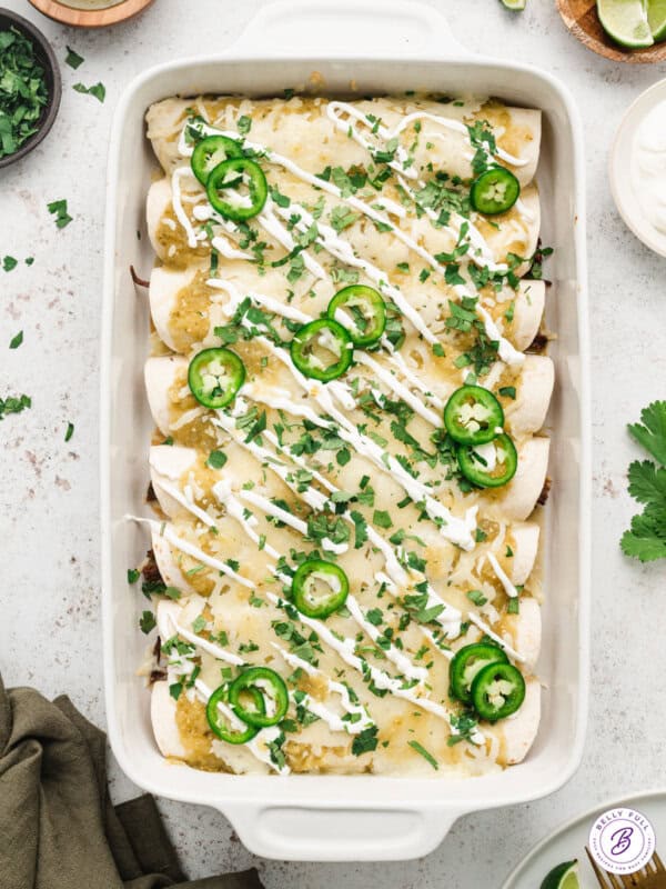 shredded beef enchiladas casserole topped with sour cream and slice jalapenos