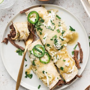 2 shredded beef enchiladas on plate with jalapeno slices