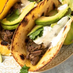 tacos with shredded beef taco topped with sour cream and avocado