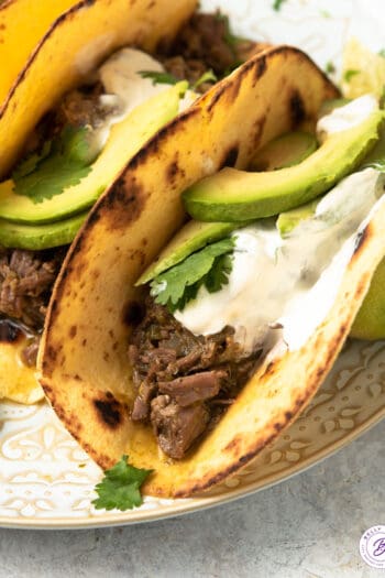 tacos with shredded beef taco topped with sour cream and avocado