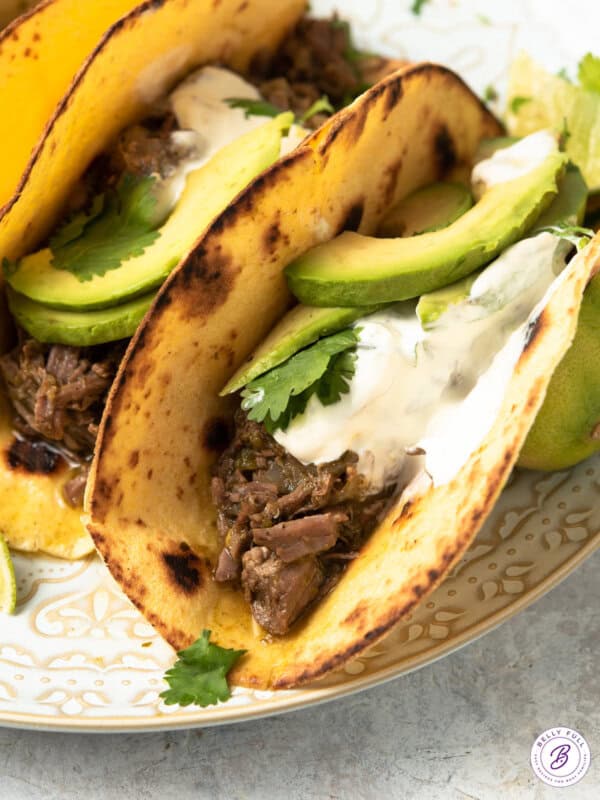 tacos with shredded beef taco topped with sour cream and avocado