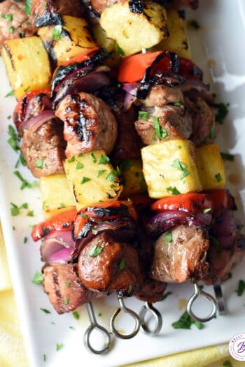 overhead stack of grilled teriyaki pork kabobs on serving tray