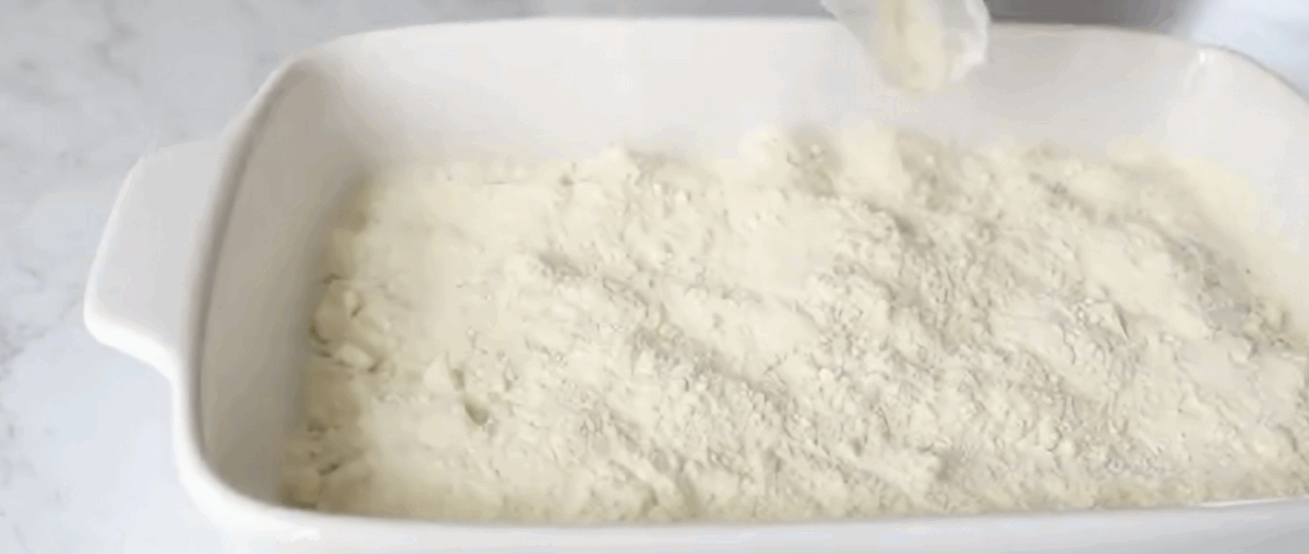 Sprinkling cake mix over the blueberries.