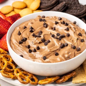 Angled view of a bowl of brownie dip on a tray with pretzels, cookies, and strawberries