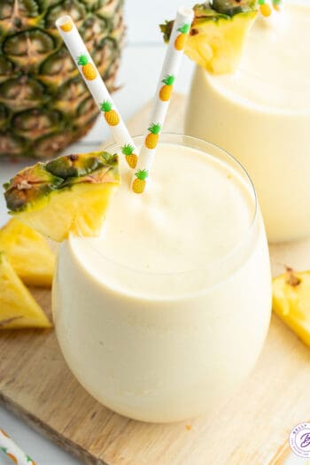 pineapple smoothie with pineapple wedge and straws