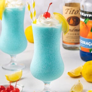 A frozen Blue Lagoon cocktail topped with whipped cream and a cherry