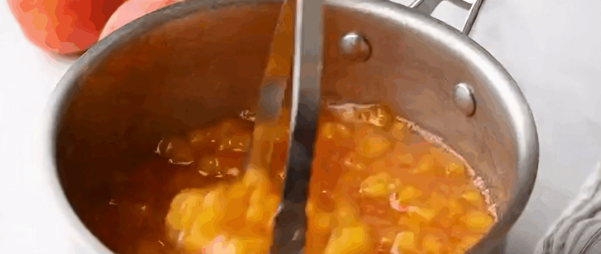 Mashing the peach mixture with a potato masher.