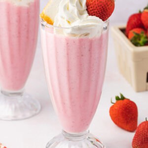 A boozy strawberry milkshake topped with whipped cream and a strawberry
