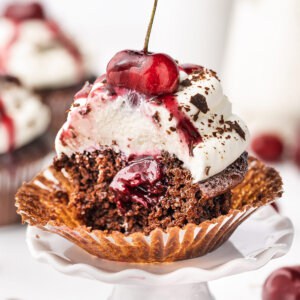 A black forest cupcake cut in half to show the cherry filling