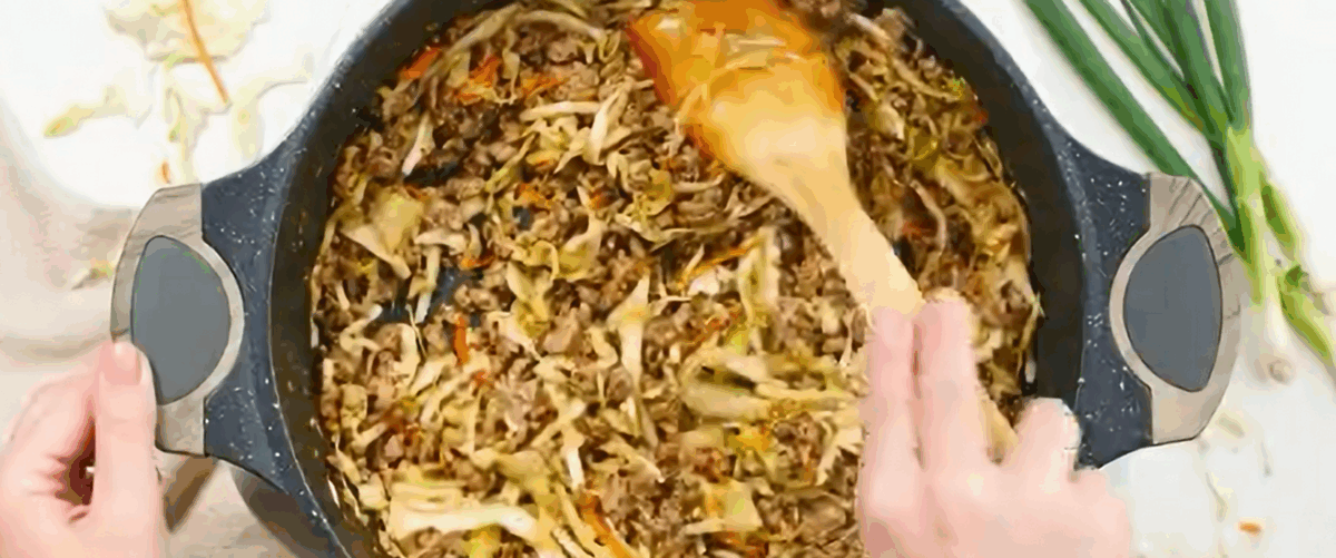 Adding coleslaw and teriyaki sauce to the pork mixture.