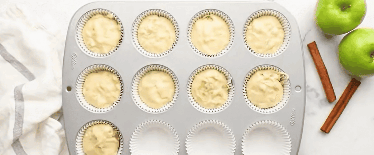 The muffin batter being poured into the lined muffin tray.