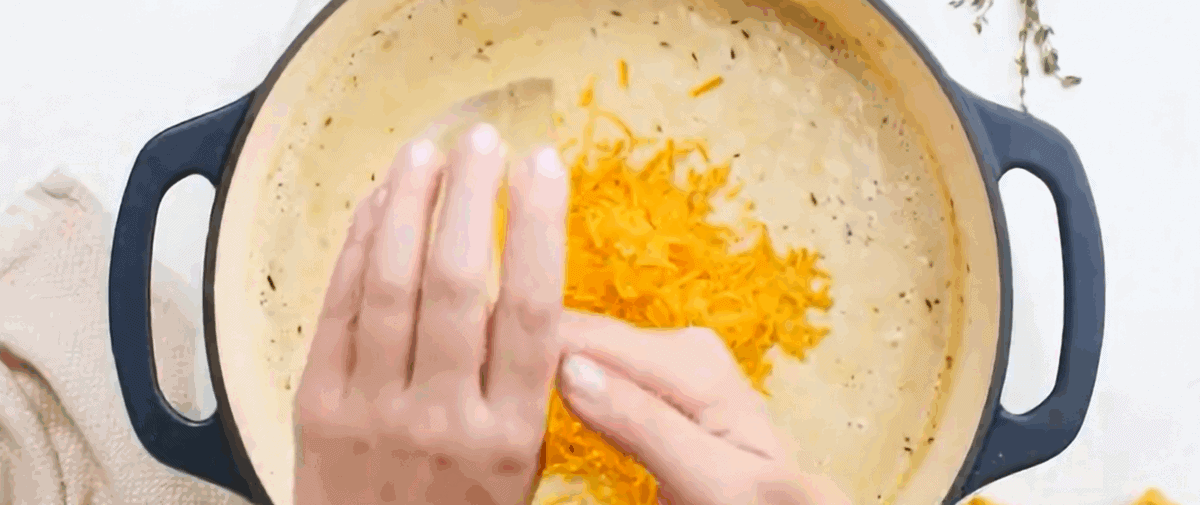 Adding grated cheese to the blended soup. 