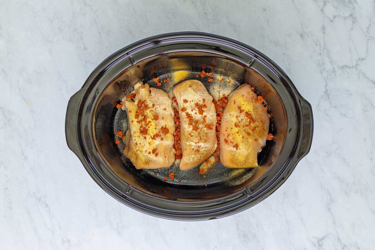 Chicken breasts with seasoning in a crockpot.