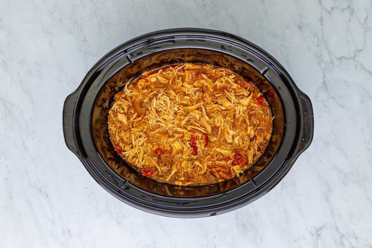 Cooked shredded chicken in a crockpot.