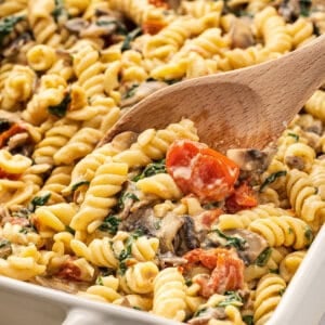 A wooden spoon stirring boursin cheese pasta