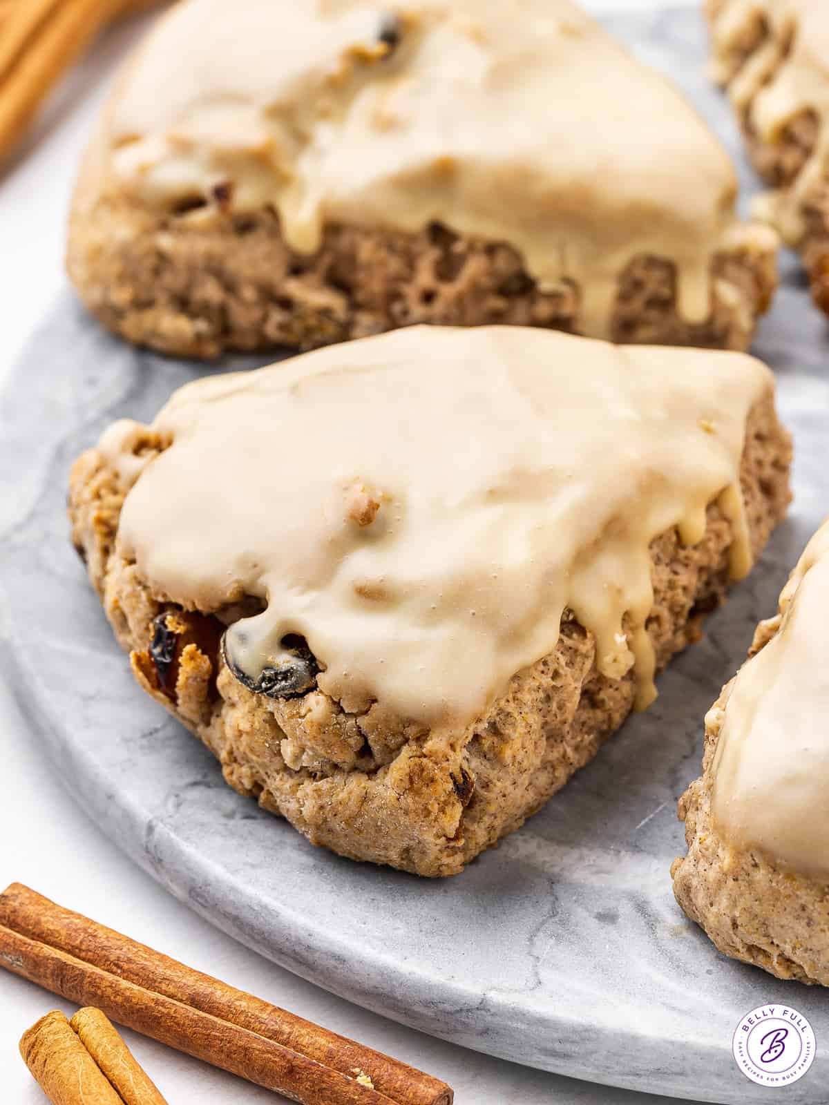 close up triangle glazed scone with raisins