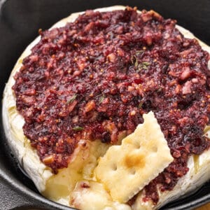 Overhead view of baked brie with a cracker in the cheese