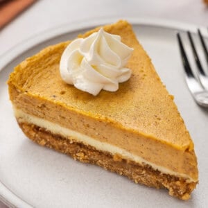 A slice of layered pumpkin cheesecake on a white plate