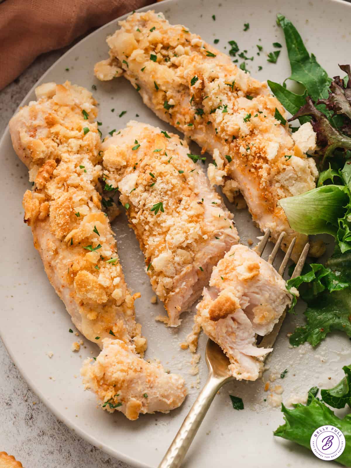 Three pieces of Ritz cracker chicken on a plate with salad