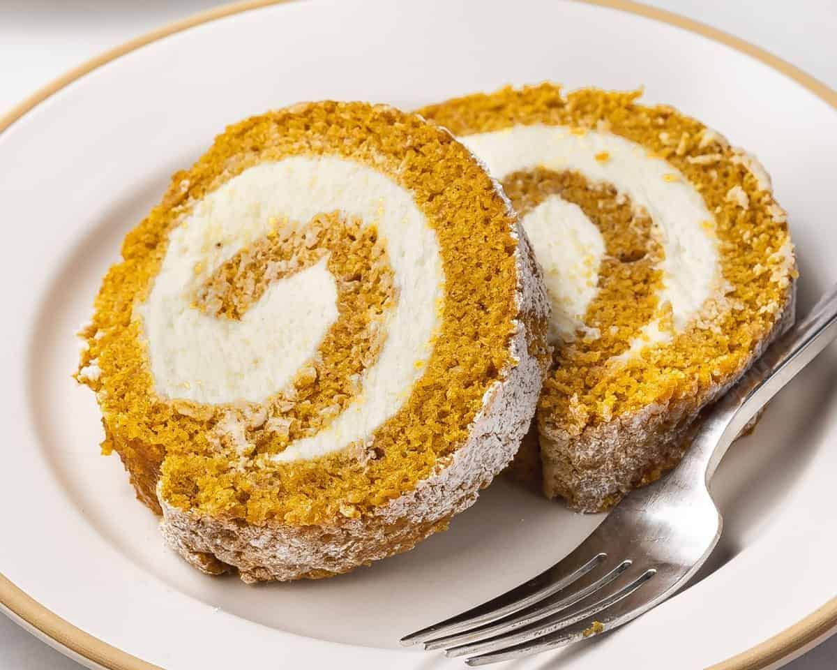 Pumpkin roll cake on a plate with a fork.