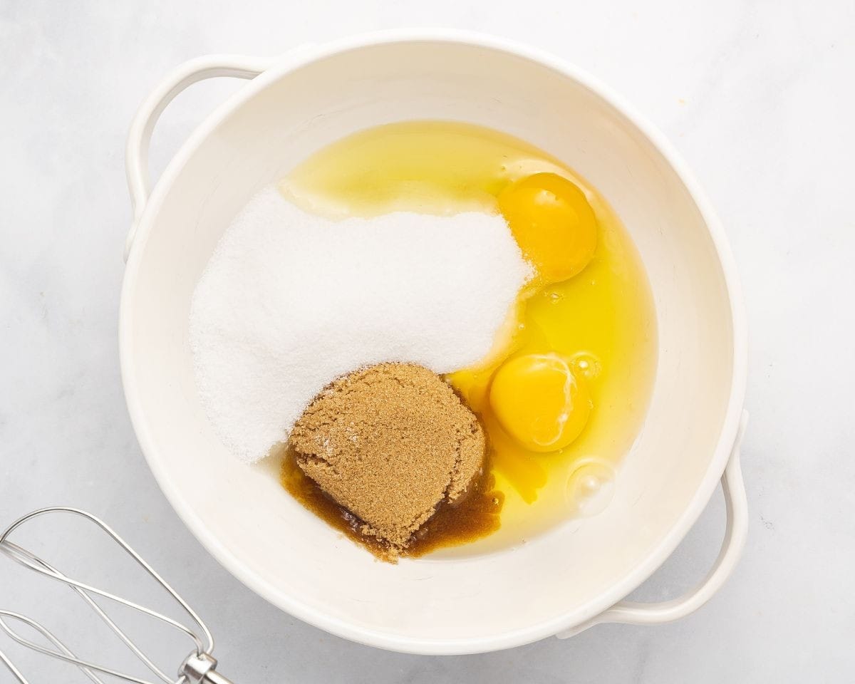 Combining eggs with the sugars and vanilla.