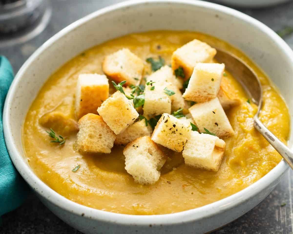 Bowl of split pea soup with croutons, and a spoon.