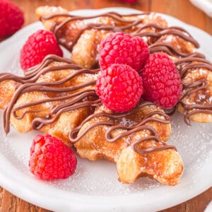 2 croffles on plate with chocolate drizzle and fresh fruit