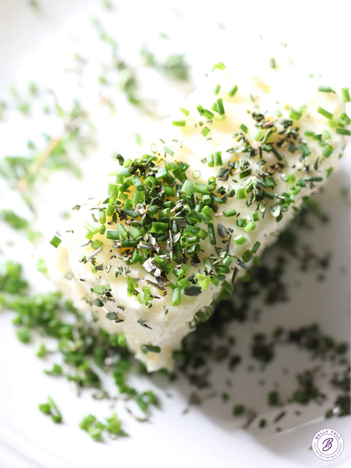 block of butter with fresh chopped herbs on top